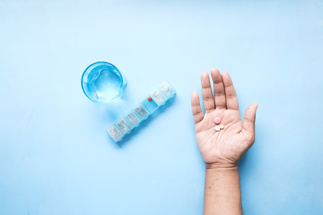 Antibiotic pills on a hand beside a glass of water