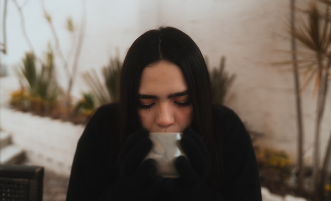 Person seated at a table with a cup, looking thoughtful