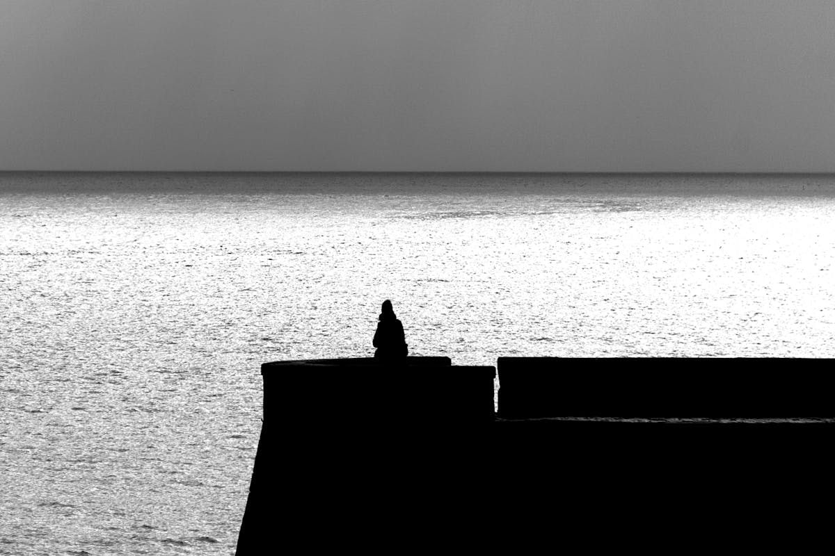 A lone silhouette by the sea at twilight