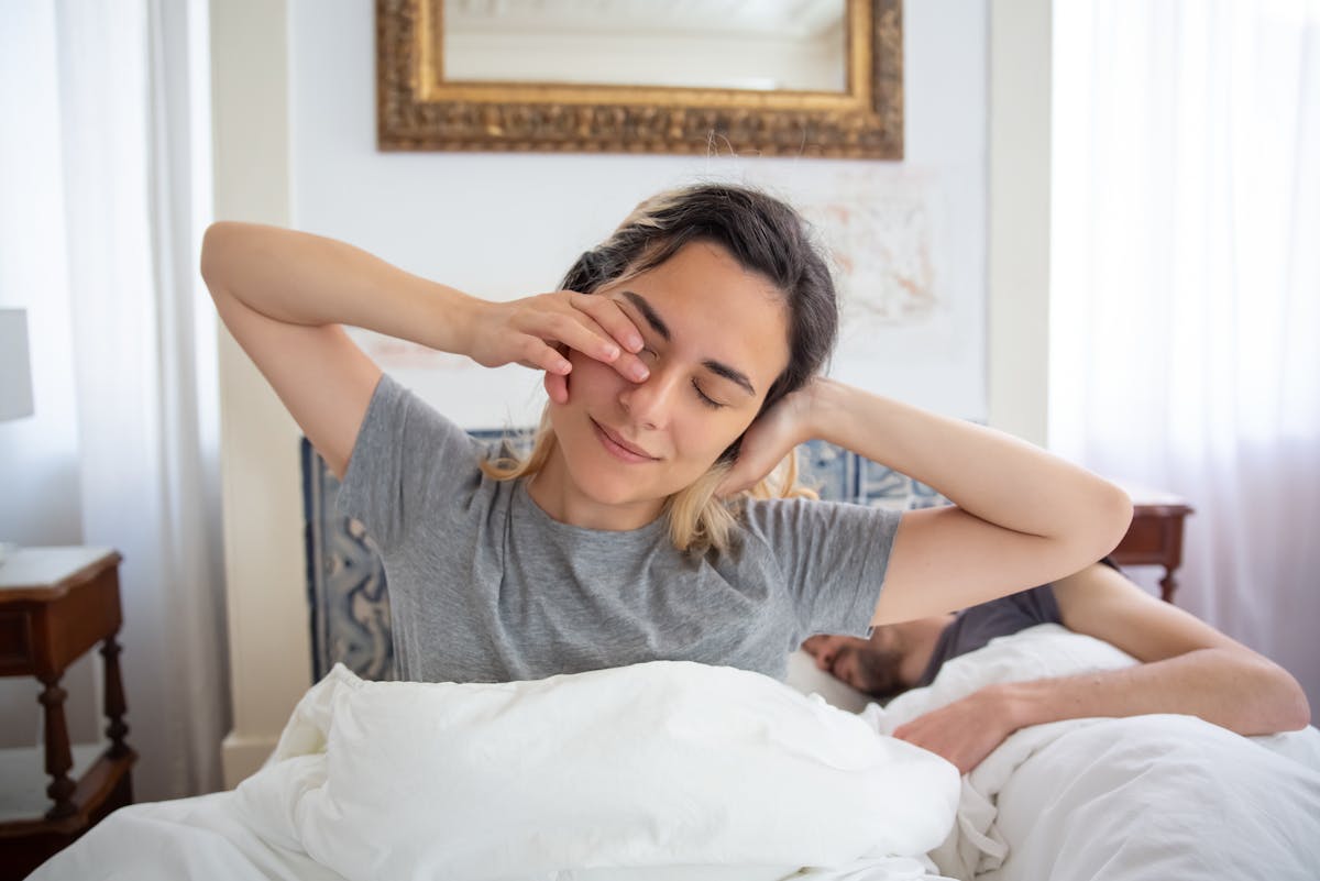 A person waking up in bed in soft morning light